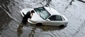 Flooded sedan sitting in deep water after heavy rainfall.