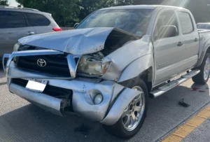 Wrecked Toyota Tacoma with severe front-end collision damage.