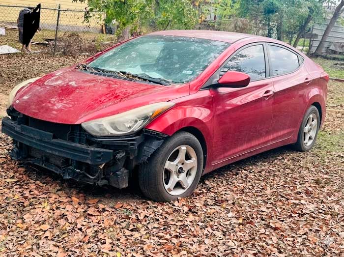 Hyundai Elantra 2014 model, con pintura desgastada y sin defensa delantera, vendido como carro yonque en Cleveland, TX, a Junk Car Buyers R-Us.