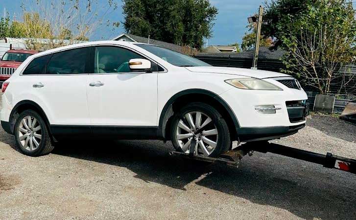 Junk Car Buyers R-Us towing a used white SUV; instant cash for cars service in South Houston, TX.
