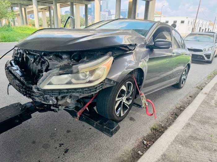 Front-end damaged Honda Accord on a tow truck in Pasadena, TX, bought by Junk Car Buyers R-Us.
