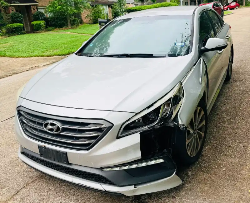 Silver damaged sedan parked in a Houston, TX neighborhood ready for as-is junk car pickup