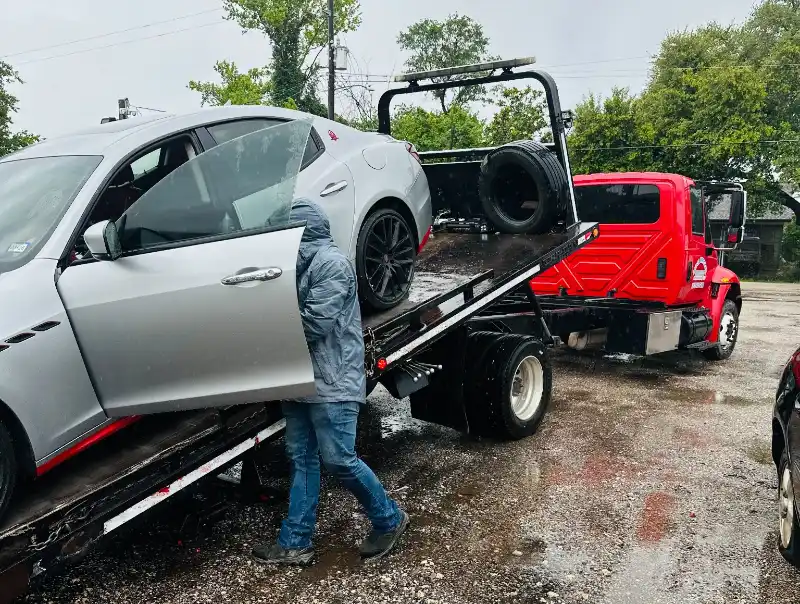 Silver car being loaded onto a tow truck for junk car pickup in Houston, TX