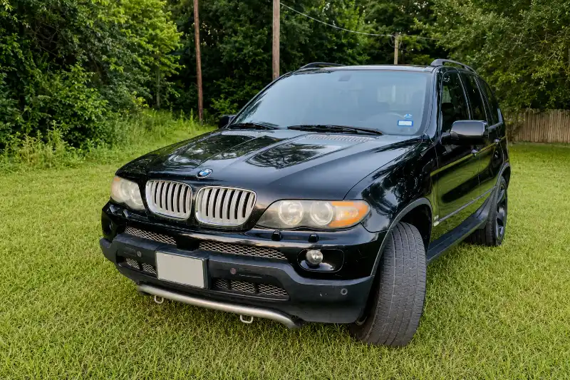 Black BMW SUV parked on grass before as-is pickup in Jersey Village, TX.