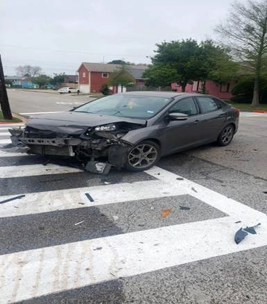 Carro gris con daños frontales asegurado sobre una plataforma de remolque en Tomball, Texas