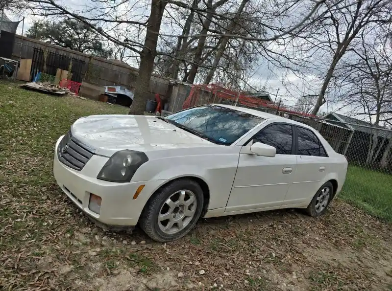 Cadillac blanco usado estacionado en una propiedad residencial.