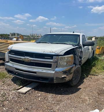 Pickup Chevrolet blanca con daño frontal estacionada en un lote de Houston