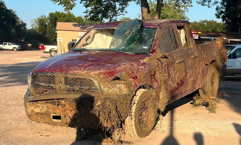 Mud-covered damaged Dodge Ram pickup truck with broken windshield in Richmond, TX.