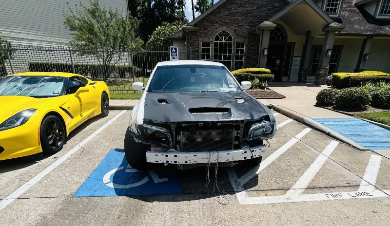 Damaged sedan missing its front bumper in an apartment parking lot in Katy, TX.