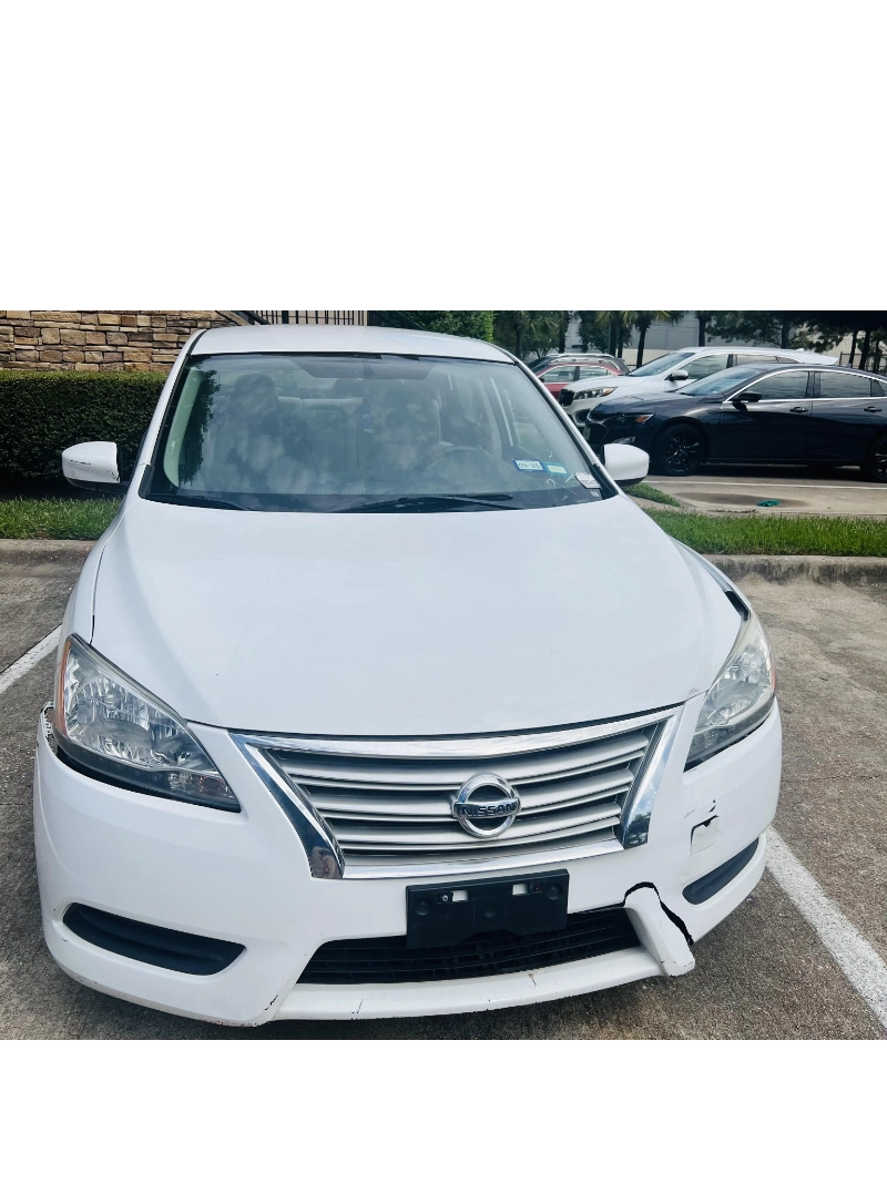 White Nissan sedan with front bumper damage at an apartment complex in Pearland, TX.
