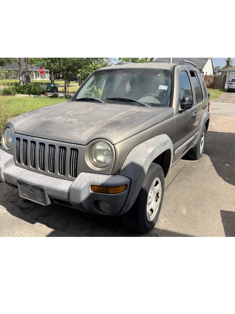 Older Jeep Liberty with exterior wear parked in a driveway in Pasadena, TX.