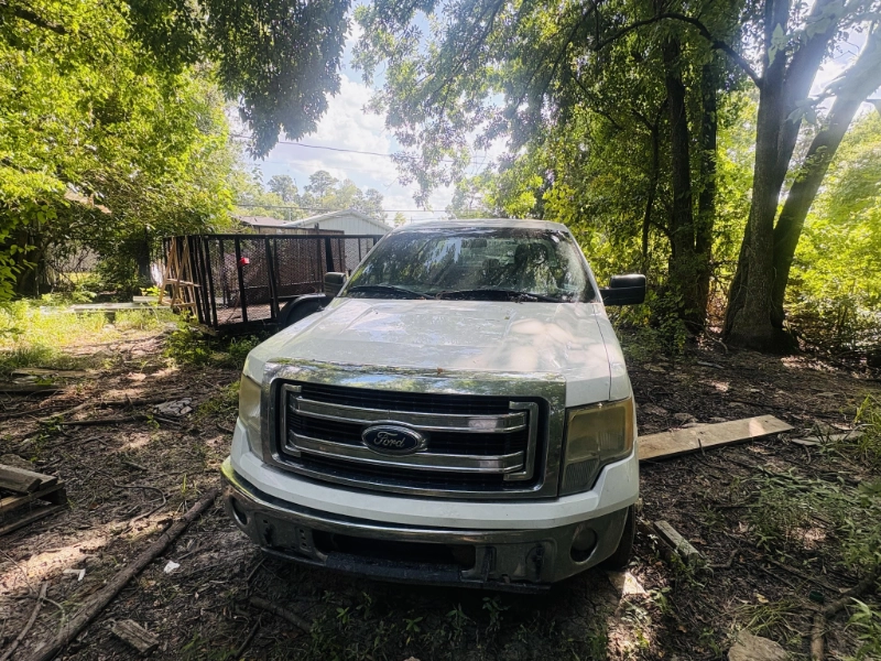 White Ford pickup truck parked on a dirt area with trees in South Houston, TX.