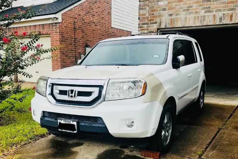 White Honda Pilot parked in a residential driveway in The Woodlands, TX.