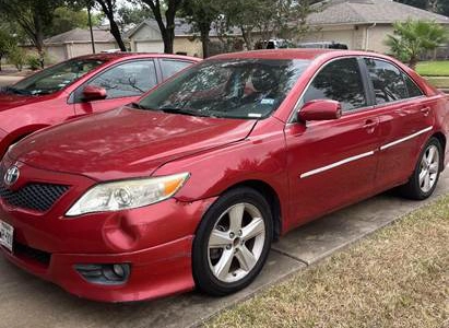 Damaged red Toyota Camry parked in a driveway in Rosenberg, TX.