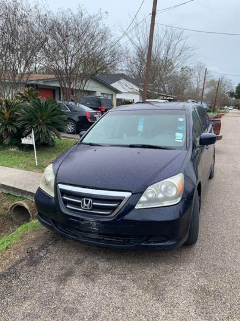 Honda Odyssey azul estacionada en una calle residencial en Alvin, TX.